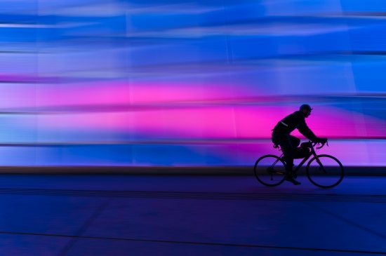 霓虹灯下一个人骑自行车的图片